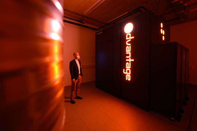 a man standing next to a black box that says Odvantage, the room is lit in an orange hue from the light from the letters on the black box