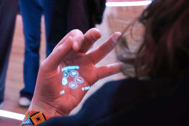 an employee demonstrates gesture control of Humane's wearable AI pin's laser ink projection at the Mobile World Congress in Barcelona